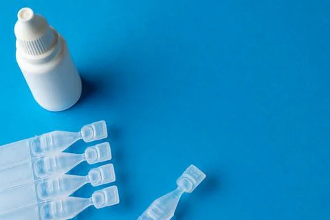 Composition of saline solution caplets and dropper bottle on blue background Stock Photos