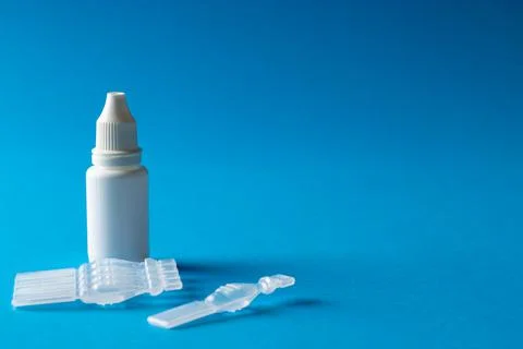 Composition of saline solution caplets and dropper bottle on blue background Stock Photos