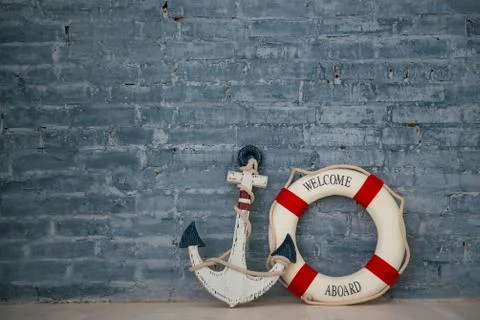 A composition on a sea theme with an anchor and life ring on a gray brick wal Stock Photos