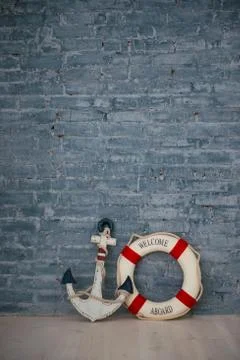 A composition on a sea theme with an anchor and life ring on a gray brick wal Stock Photos