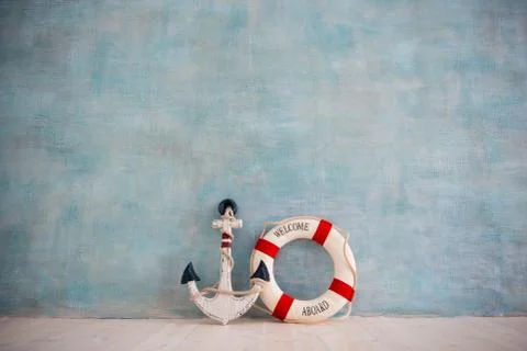 A composition on a sea theme with an anchor and lifebuoy on a blue wall Stock Photos