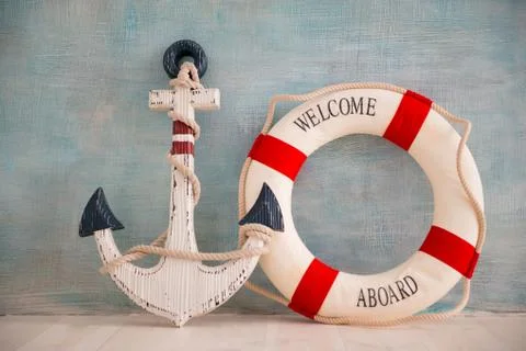 A composition on a sea theme with an anchor and lifebuoy on a blue wall Stock Photos