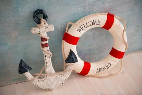 A composition on a sea theme with an anchor and lifebuoy on a blue wall Stock Photos