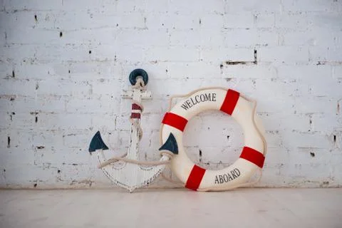 A composition on a sea theme with an anchor and life ring on a white brick wa Stock Photos