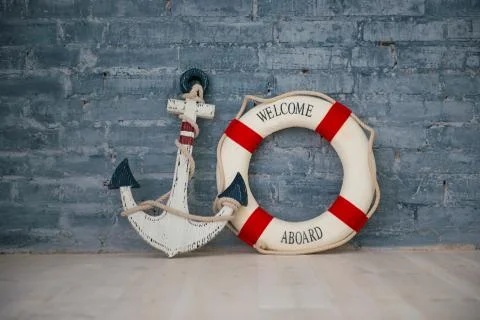 A composition on a sea theme with an anchor and life ring on a gray brick wal Stock Photos