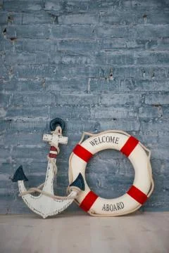 A composition on a sea theme with an anchor and life ring on a gray brick wal Stock Photos