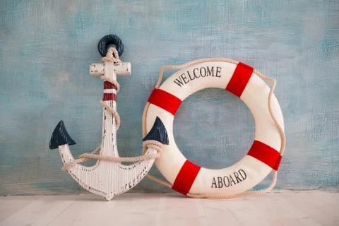 A composition on a sea theme with an anchor and lifebuoy on a blue wall Stock Photos