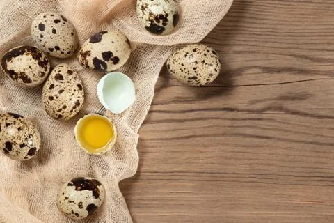 Composition of several quail eggs on decorative fabric on a wooden table, cop Stock Photos
