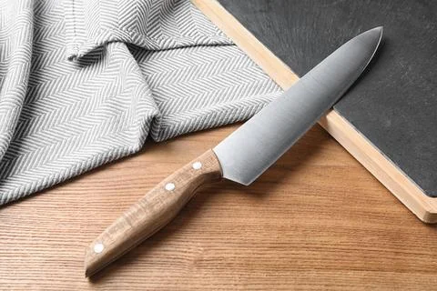 Composition with sharp chef's knife and board on wooden background Stock Photos