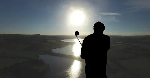 Composition of silhouette of golf player over landscape and blue sky with copy Fotos Stock