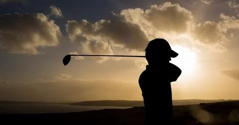 Composition of silhouette of golf player over landscape and clouds on blue sky Fotos Stock