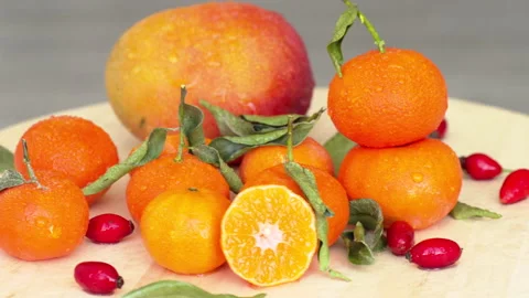 Composition with sliced rotating oranges, mango, rosehip and green leaves, close Stock Footage 166132537