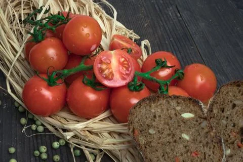 Composition of small red cherry tomatoes on an old wooden table in a rustic s Photos