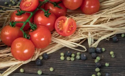 Composition of small red cherry tomatoes on an old wooden table in a rustic s Stock Photos