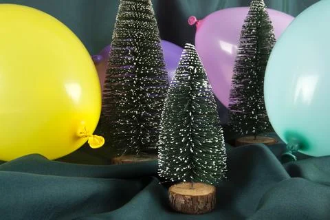 A composition of snowy Christmas trees surrounded by multicolored balloons .. Stock Photos