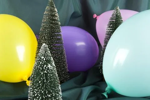 A composition of snowy Christmas trees surrounded by multicolored balloons .. Stock Photos