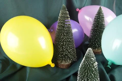 A composition of snowy Christmas trees surrounded by multicolored balloons .. Stock Photos