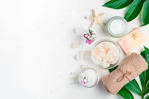 A composition with a spa set, flowers and leaves on a light gray background. Stock Photos