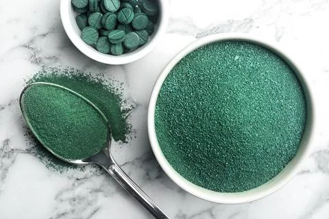 Composition with spirulina algae powder and pills on marble background, top v Foto stock