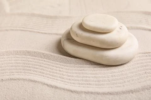 Composition with stack of spa stones and lines on sand as background, closeup Stock Photos