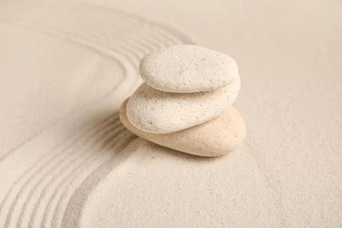 Composition with stack of spa stones and lines on sand as background, closeup Stock Photos