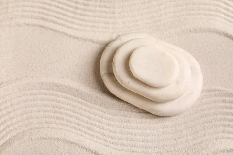 Composition with stack of spa stones and lines on sand as background, closeup Stock Photos