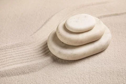 Composition with stack of spa stones and lines on sand as background, closeup Stock Photos