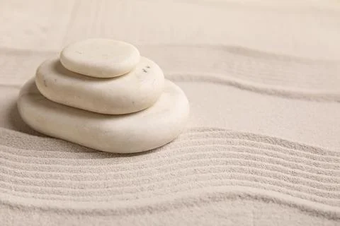 Composition with stack of spa stones and lines on sand as background, closeup Stock Photos