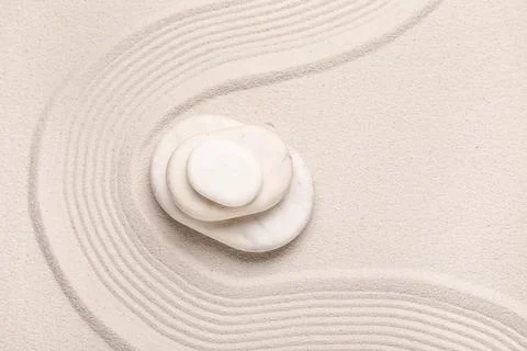 Composition with stack of spa stones and lines on light sand as background, c Stock Photos
