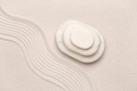 Composition with stack of spa stones and lines on light sand as background, c Stock Photos