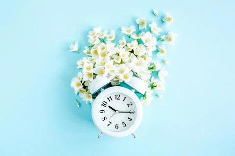 Composition-Summer time from Jasmine flower and clock, alarm on blue background 스톡 사진