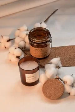 Composition on the table. candles in brown jars, a cotton branch and a cork b Stock Photos