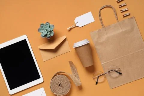 Composition with tablet computer, cup of coffee and delivery paper bag on ora Stock Photos