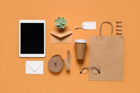 Composition with tablet computer, cup of coffee and delivery paper bag on ora Stock Photos