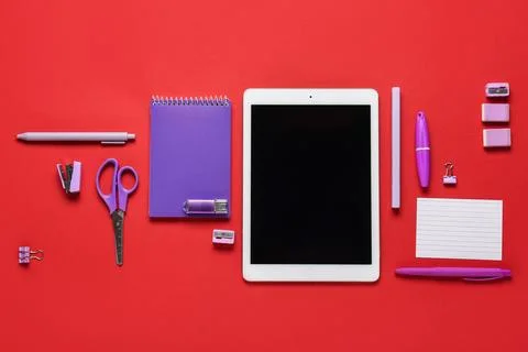 Composition with tablet computer, stationery and modern flash drive on red ba Stock Photos