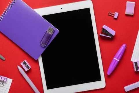 Composition with tablet computer, stationery and modern flash drive on red ba Stock Photos