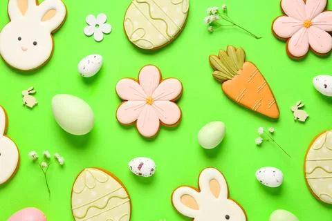 Composition with tasty Easter cookies, eggs and flowers on green background Stock Photos