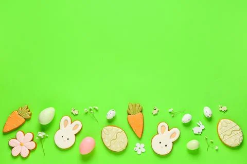 Composition with tasty Easter cookies, eggs and flowers on green background Stock Photos