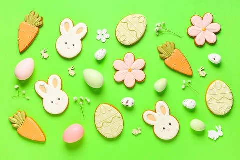 Composition with tasty Easter cookies, eggs and flowers on green background Stock Photos