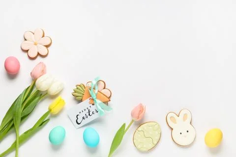Composition with tasty Easter cookies, eggs and tulip flowers on white backgr Stock Photos