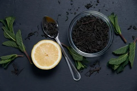 Composition of a tea in the glass bowl with mint and lemon on a dark background Stock Photos