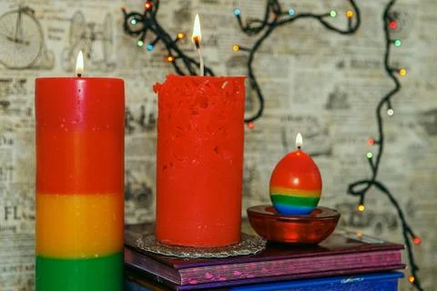 Composition of the three burning rhandmade candles among colorful books. Stock Photos