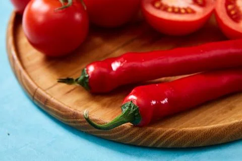 Composition of tomato bunch and halves and sweet pepper on wooden plate, top Stock Photos
