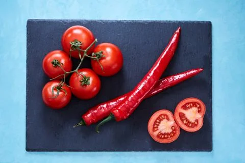 Composition of tomato bunch and halves togather with sweet pepper on black board Stock Photos