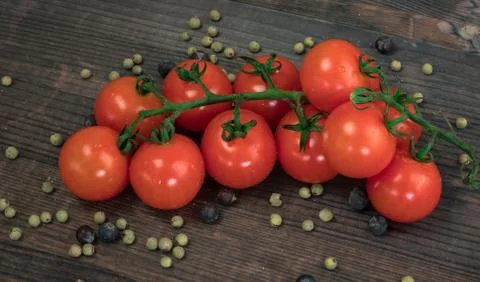 Composition from tomato. Fresh cherry tomatoes on a wooden table with spices. Stock Photos