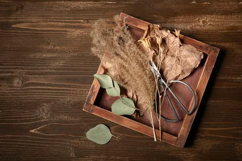 Composition with tray, scissors and beautiful dried flowers on brown wooden b Stock Photos