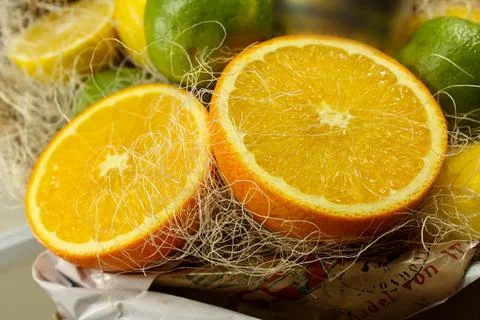 Composition of two halves of oranges, green limes and yellow lemons in the ba Stock Photos