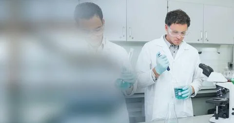 Composition of two male scientists in lab using pipette and test tubes with Foto stock