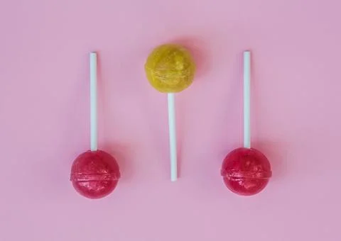 Composition of two red lollipops and a yellow one isolated on the pink backgroun Stock Photos