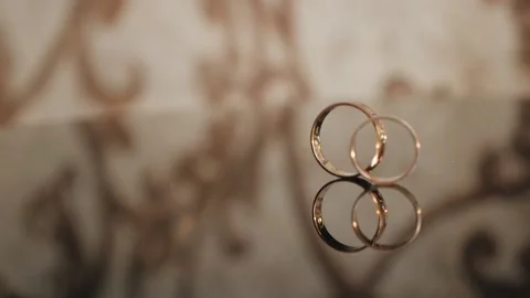 Composition of two wedding gold rings at the table. ring is rolling to another. Stock Footage 132028869